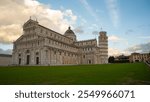 The Leaning Tower of Pisa and Pisa Cathedral in The Piazza dei Miracoli, showcasing Romanesque architecture under a cloudy sky.