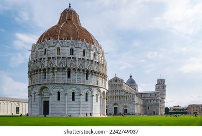 Leaning tower of Pisa Italy with Basilica Cathedral on a bright summer day with green grass low angle. 