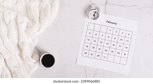 Leap year concept, calendar, alarm clock and coffee on light top view web banner