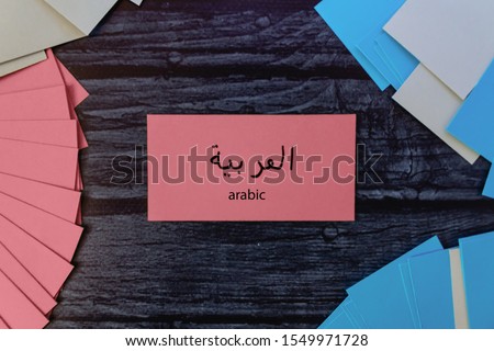 Learn Arabic. Colored cards for learning words on a dark wooden table. Pink