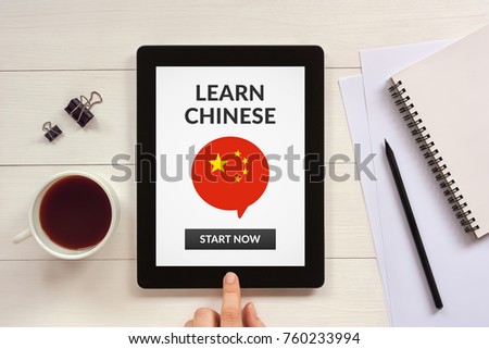 Learn Chinese concept on tablet screen with office objects on white wooden table.  Flat lay