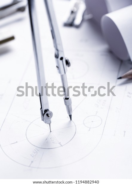 Learn to draw circles with a compass. Compasses and\
Architect scale ruler placed on the desk, filled with building\
plans. selective focus