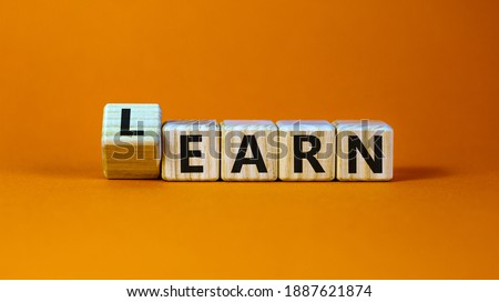 Learn or earn symbol. Turned a cube and changed the word 'earn' to 'learn'. Beautiful orange background. Business and learn or earn concept. Copy space.