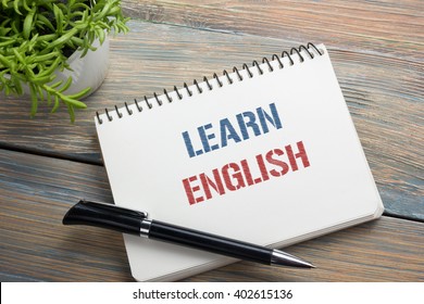 Learn English Text written on notebook page, red pencil and coffee cup. Office desk table top view