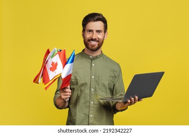 Learn Foreign Languages. Happy Man Holding Laptop And International Flags, Middle Aged Male Teacher With Computer, Enjoying Distance Learning, Yellow Background