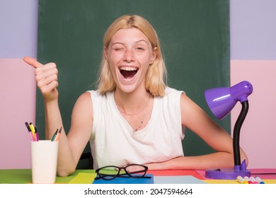 Learn With Fun. Funny Female Teacher Sitting At Her Workplace And Teaching English. Happy Funny Teacher Winking. Education Concept. Good Idea.