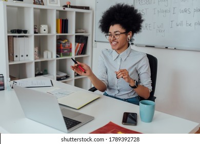 Learn with fun. Happy afro american female teacher sitting at her workplace and teaching English online, looking at computer screen and laughing. Focus on a woman. E-learning. Distance education