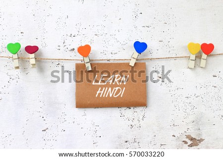 LEARN HINDI - concept words on paper with wooden clamps. rustic wooden background