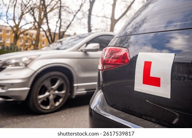 Learner driver L plates attached to car on urban road in the United Kingdom