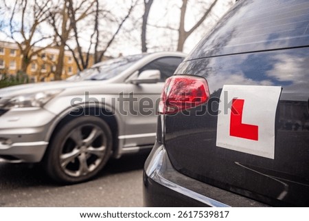 Learner driver L plates attached to car on urban road in the United Kingdom
