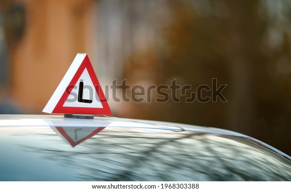 Learner driver school. Car\
with driving school sign, L learner driver plate on roof. Driving\
school concept, driver\'s license, traffic rules. Driver\'s education\
car sign.