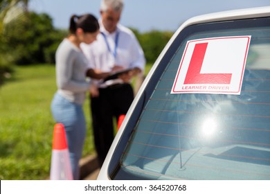 learner driver sign on a car with student and instructor standing behind