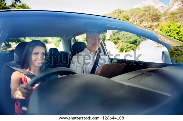 Learner driver student driving car with\
instructor. happy and confident smiling\
girl