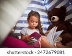 Learning, child and reading book in home tent for education, language development or knowledge in bedroom. Girl, fairytale and studying fantasy story, information or hobby with teddy bear in house