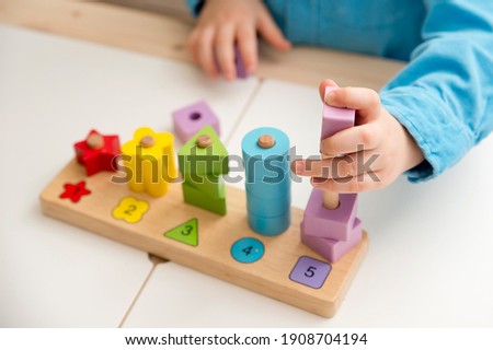 Learning counting, shapes and colors. Montessori  type implement. wooden toys. Boy puts on figures on poles.