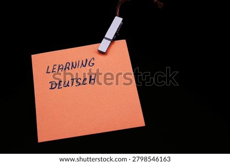 learning deutsch write on orange card on black background 