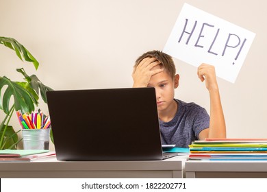 Learning Difficulties, School, Education, Online Remote Learning Concept. Sad Kid Sitting At Table With Laptop Computer And Holding Card With Help Word