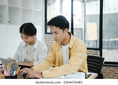 Learning, education and school concept. Young woman and man studying for a test or an exam. Tutor books with friends. Young students campus helps friend catching up and learning. - Shutterstock ID 2364476481