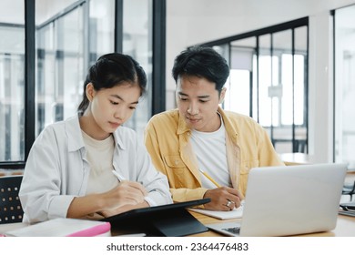 Learning, education and school concept. Young woman and man studying for a test or an exam. Tutor books with friends. Young students campus helps friend catching up and learning. - Shutterstock ID 2364476483