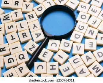 Learning English concept. Square letter tiles with magnifying glass against blue background. - Shutterstock ID 2253764311