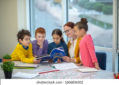 Learning English Grammar. Children Reading A Book During Their English Class