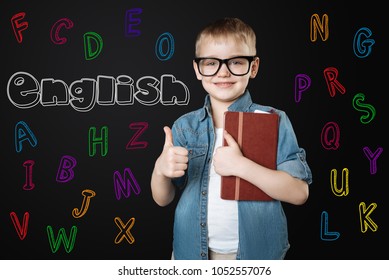 Learning English. Positive Enthusiastic Little Boy Looking Happy And Putting His Thumb Up While Waiting For His Favorite English Lesson