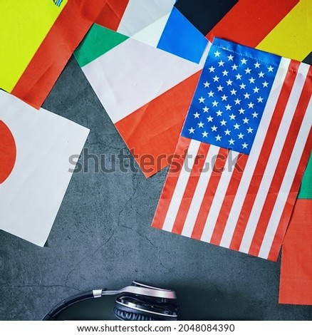 Learning foreign languages. Audio language courses. Background from countries flags and headphones on table.
