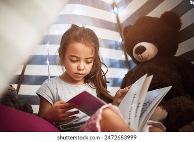 Learning, kid and reading book in home tent for education, language development or knowledge in bedroom. Girl child, fairytale or studying fantasy story, information or hobby with teddy bear in house - Powered by Shutterstock