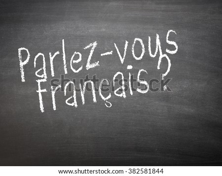 Learning language - French. Learning French language concept of teacher or student writing parlez-vous francais (do you speak French) on blackboard / chalkboard.