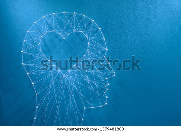Learning to love\
concept. Network of pins and threads in the shape of a cut out\
heart inside a human head symbolising that love is the core of our\
being and has its own\
logic.