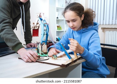 Learning New Stuff About Mechanics And Hydraulics. Working On School Assignment. Teenager Girl Build Robot Hydraulic Excavator Bucket Learning At Table At STEM Engineering Science Education Class.