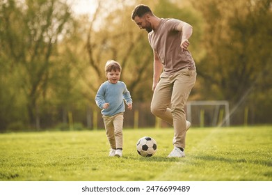 Learning to play soccer. Happy father with son are having fun on the field at summertime. - Powered by Shutterstock