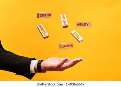 Learning Skills Concept. A Man Throws Up Wooden Blocks With The Inscriptions Skill, Knowledge, Ability, Competence, Education