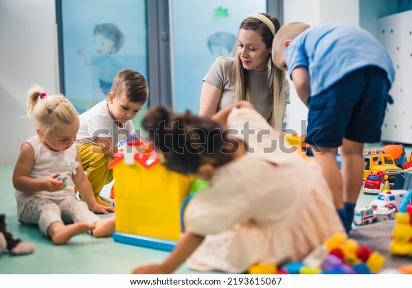 Learning through play at the nursery school.\
Toddlers and their teacher playing with colorful plastic\
playhouses, building blocks, cars and boats. Imagination,\
creativity, fine motor and gross\
motor