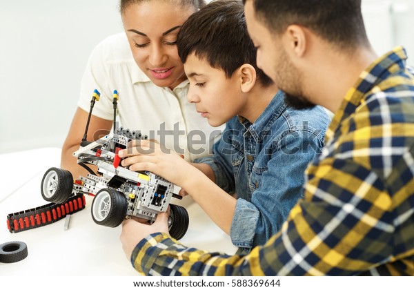 Learning together. Beautiful African woman and\
her husband helping their son building a toy car family bonding\
togetherness happiness education technology robots toys modern\
parenthood kids\
concept