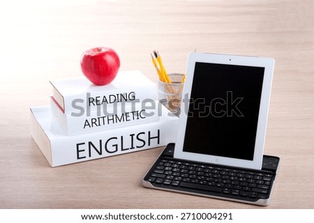 Learning tools on a desk with an apple, books, and a tablet for students