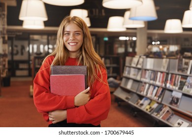 Learning, University And New Skills Concept. Cheerful Smiling, Readhead Girl Holding Books, Standing In Library Or Bookstore, Prepare Homework, Do Research For College Project