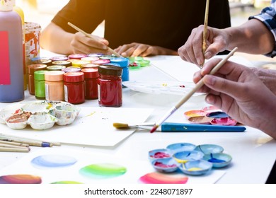 Learning to use poster color to draw various pictures of asian boys on a table outside classroom with his female art teacher, raising teen and adult helps kids school project concept. - Powered by Shutterstock