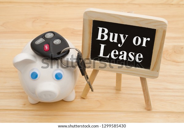 Learning whether to\
buy or lease car, A piggy bank on a desk with chalkboard and car\
keys with text Buy or\
Lease