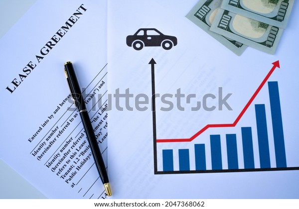 lease\
agreement,  rising car prices concept. lease agreement money and\
pen. top view and white bakcground. close\
up.