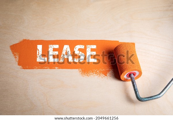 Lease concept. Orange paint and paint roller on a\
wooden surface