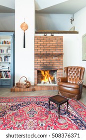 Leather Armchair In Cozy Room With Red Brick Fireplace