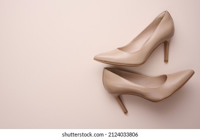 leather beige high heel shoes on a beige background, top view