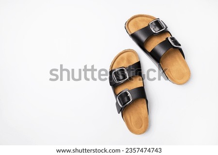 Leather black sandals birkenstocks on white background top view flat lay. Unisex summer shoes, genuine leather flip flops with cork soles. Stylish fashion footwear for city or beach