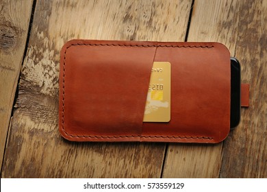 Leather Case With Mobile Phone And Credit Card On Wooden Background