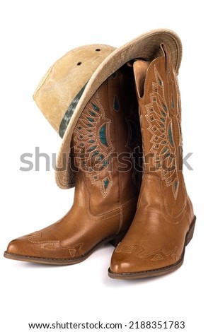 Leather cowgirl boots with embroidery and hat isolated on white background.