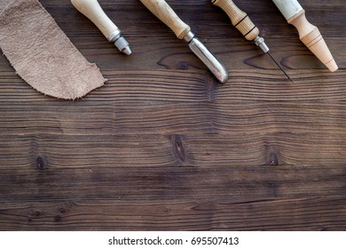 Leather craft. Knife, awl and other tools on dark wooden background top view copyspace - Shutterstock ID 695507413