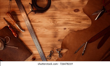 Leather craft. Tanner's tools on grey wooden background top view. Copyspace.
