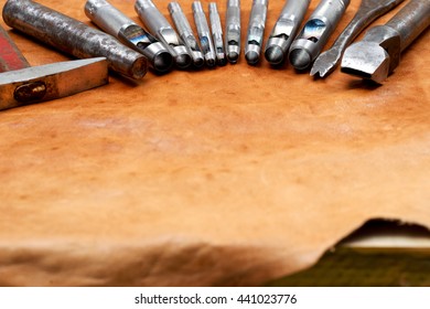 Leather craft tools on a leather background. Craftsman work desk . Piece of hide and working handmade tools on a work table. Top view. Copy space. - Powered by Shutterstock