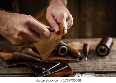 Leather craft tools on the old wood table in a shed. Leather craftsman workspace. Grounge dark wood texture background. - Powered by Shutterstock